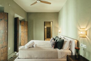 A hotel room with a bed, a wooden wardrobe, a ceiling fan, and a wall-mounted lamp. - Casa Torno - El Mirador (Sanlúcar de Barrameda)