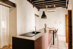 A kitchen with a sink, a pendant light, and a dining area with chairs and a table. - Casa Torno - El Mirador (Sanlúcar de Barrameda)