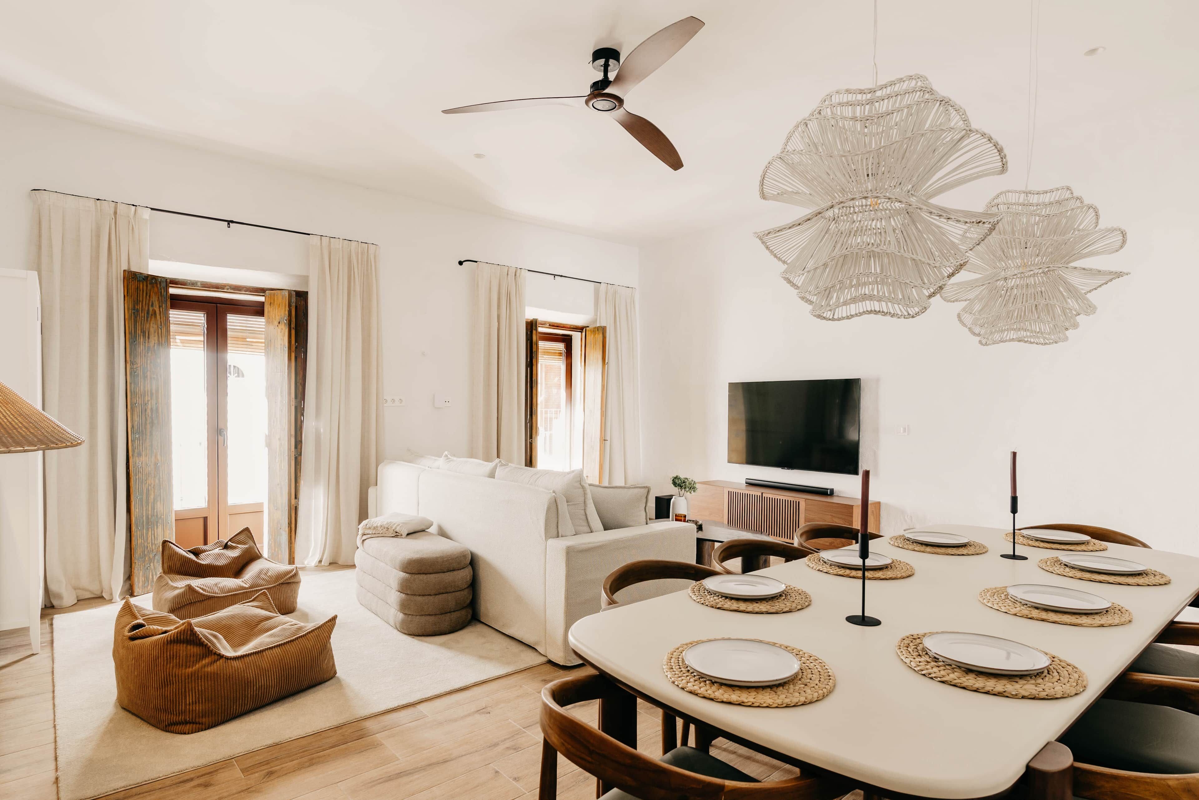 A modern living room with a sofa, a dining table set for six, and a television.