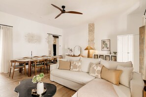 A modern living room with a sofa, dining table, and ceiling fan. - Casa Torno - El Mirador (Sanlúcar de Barrameda)