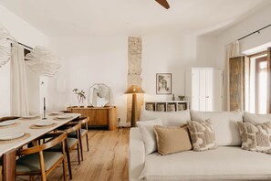 A cozy living room with a dining area, a fireplace, and a large window. - Casa Torno - El Mirador (Sanlúcar de Barrameda)