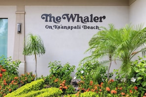 A hotel sign with 'The Whaler On Ka'anapali Beach' and a landscaped garden with various plants and flowers. - Whaler | Ocean View Studio | Kaanapali Beach | Car Incl. w/ 6+ Nights | WH2-465 by KBM (Lahaina)