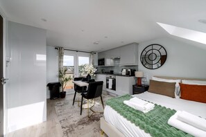 A modern hotel room with a bed, a desk, and a kitchenette. - Greenford Apartments (Wembley)