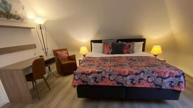 Un dormitorio con cama, lámparas de noche, escritorio y silla.