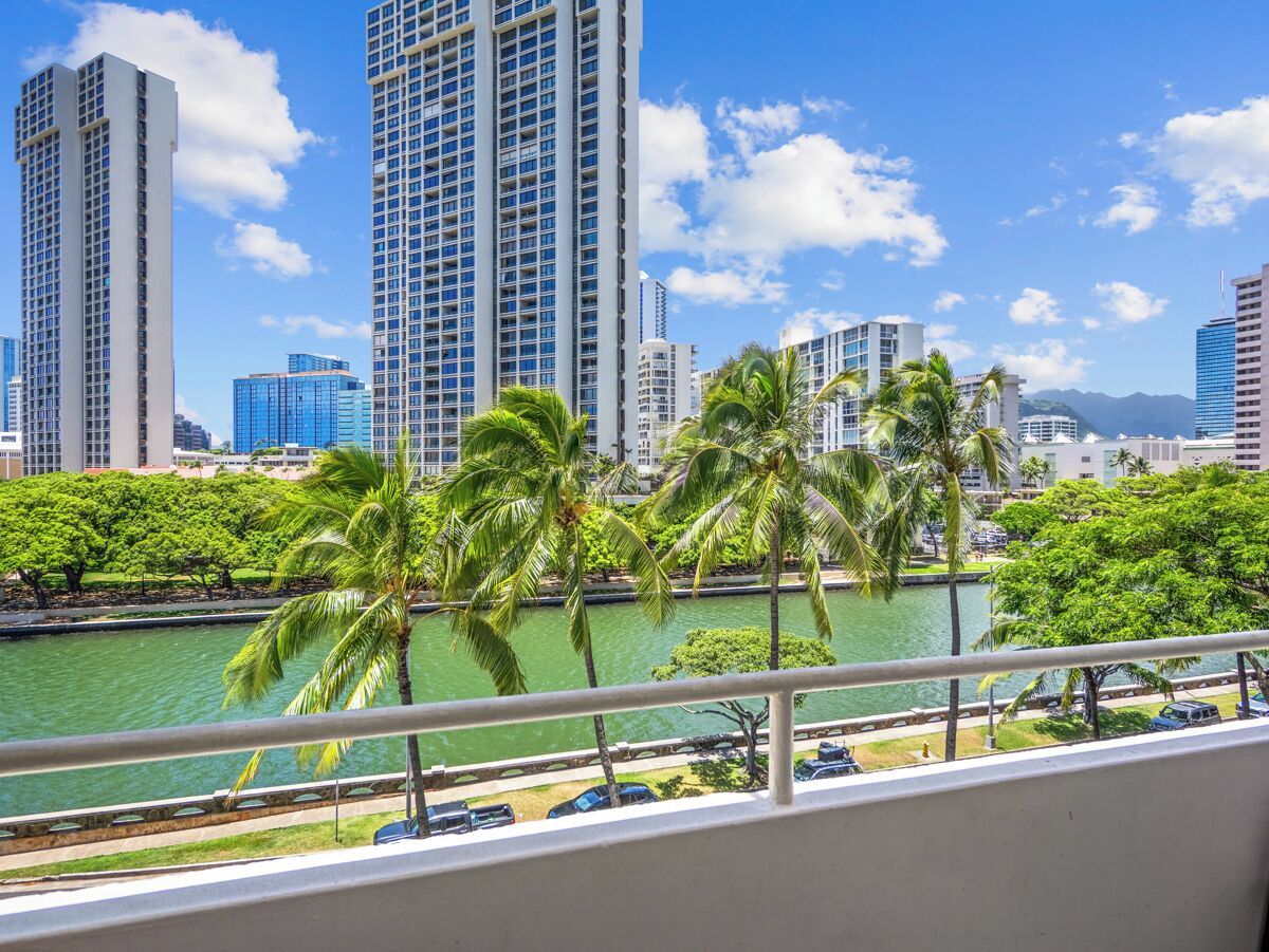 A cityscape with tall buildings, a body of water, and palm trees.