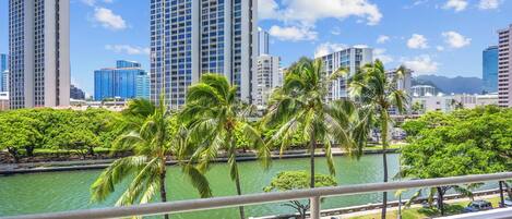 A cityscape with tall buildings, a body of water, and palm trees.
