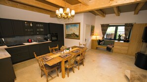 A kitchen with dark cabinets, a wooden dining table, and a chandelier. - Exclusive Vacation Home on Lake Roofensee—Fireplace, Designer Kitchen, and Idyllic Natural Setting (Stechlin)