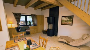 A cozy living room with a wooden dining table, chairs, a sofa, a fireplace, and a staircase. - Exclusive Vacation Home on Lake Roofensee—Fireplace, Designer Kitchen, and Idyllic Natural Setting (Stechlin)