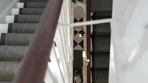 A staircase with a handrail, metal railings, and a patterned floor. - Guestready - The Crescent (London)