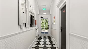 A hallway with a checkered floor, white walls, and a door with a red sign.
