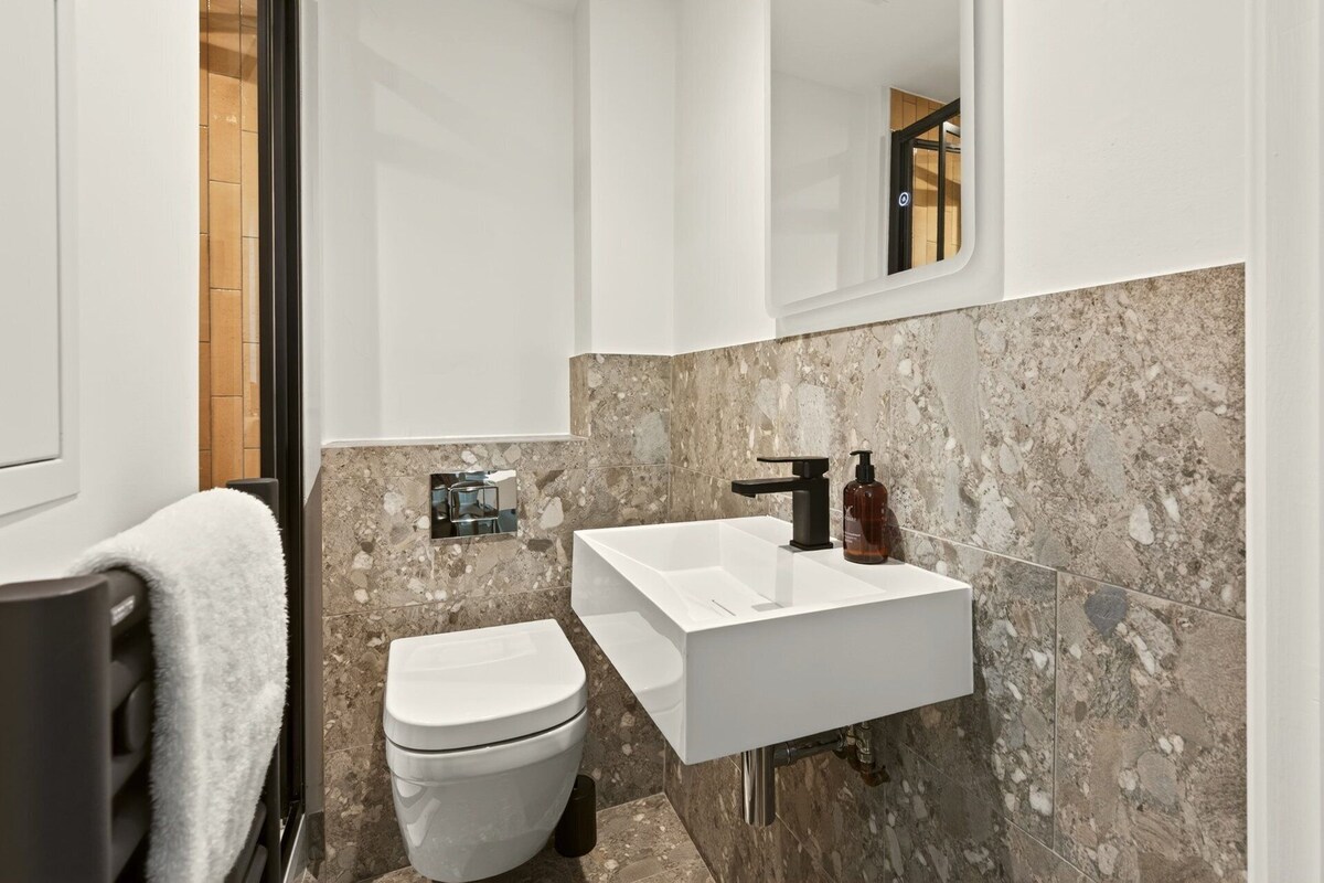 Un bagno con un WC bianco, un lavandino bianco e una parete in marmo.