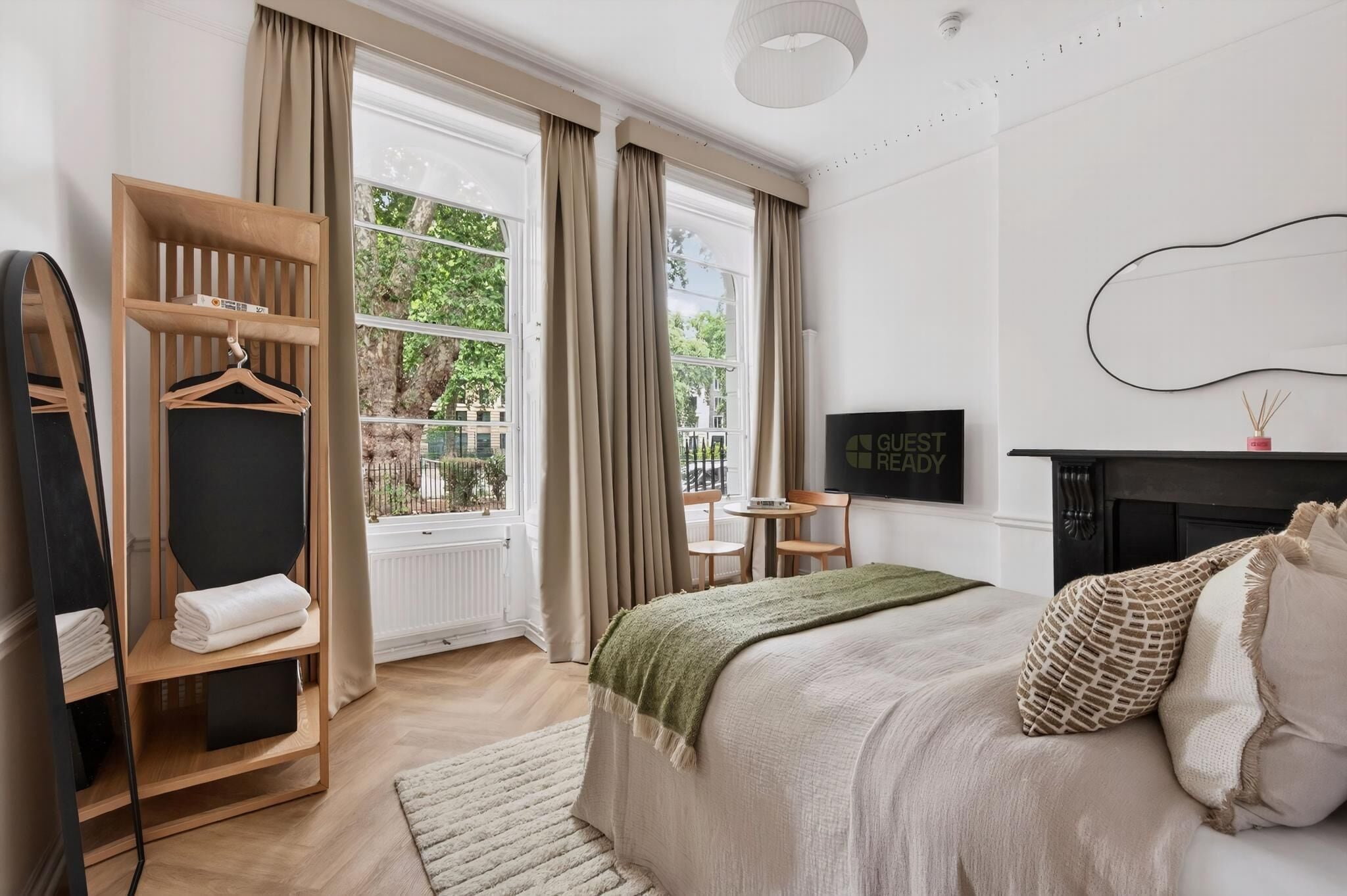 A modern hotel room with a bed, a seating area, a wardrobe, and a television.