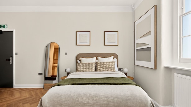 A bedroom with a bed, a mirror, a door, and framed artwork on the wall. - Guestready - The Crescent (London)