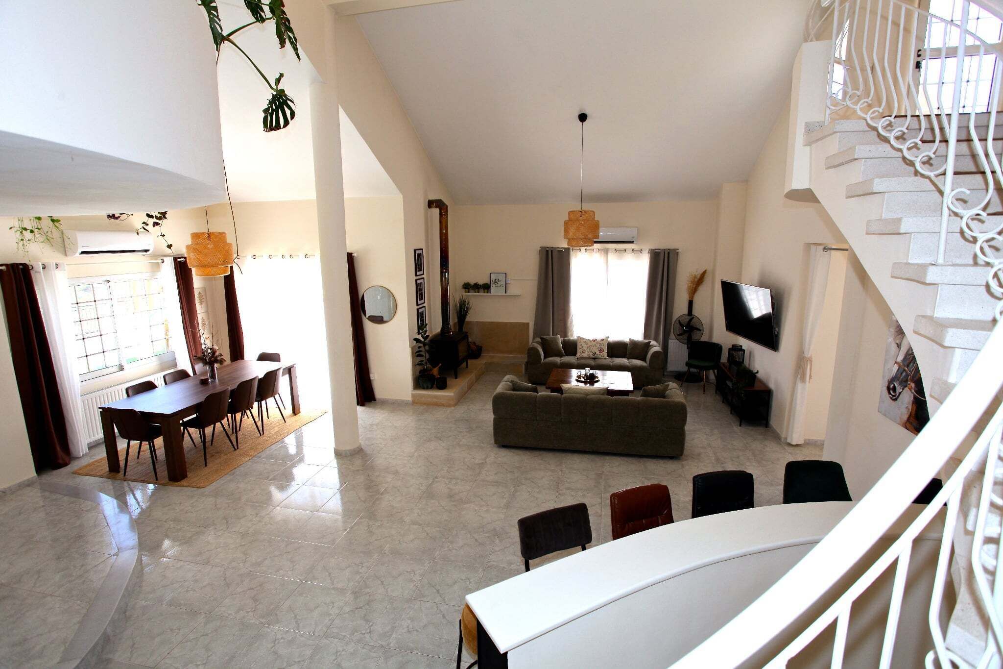 A spacious living area with a dining table, sofa, and a staircase.