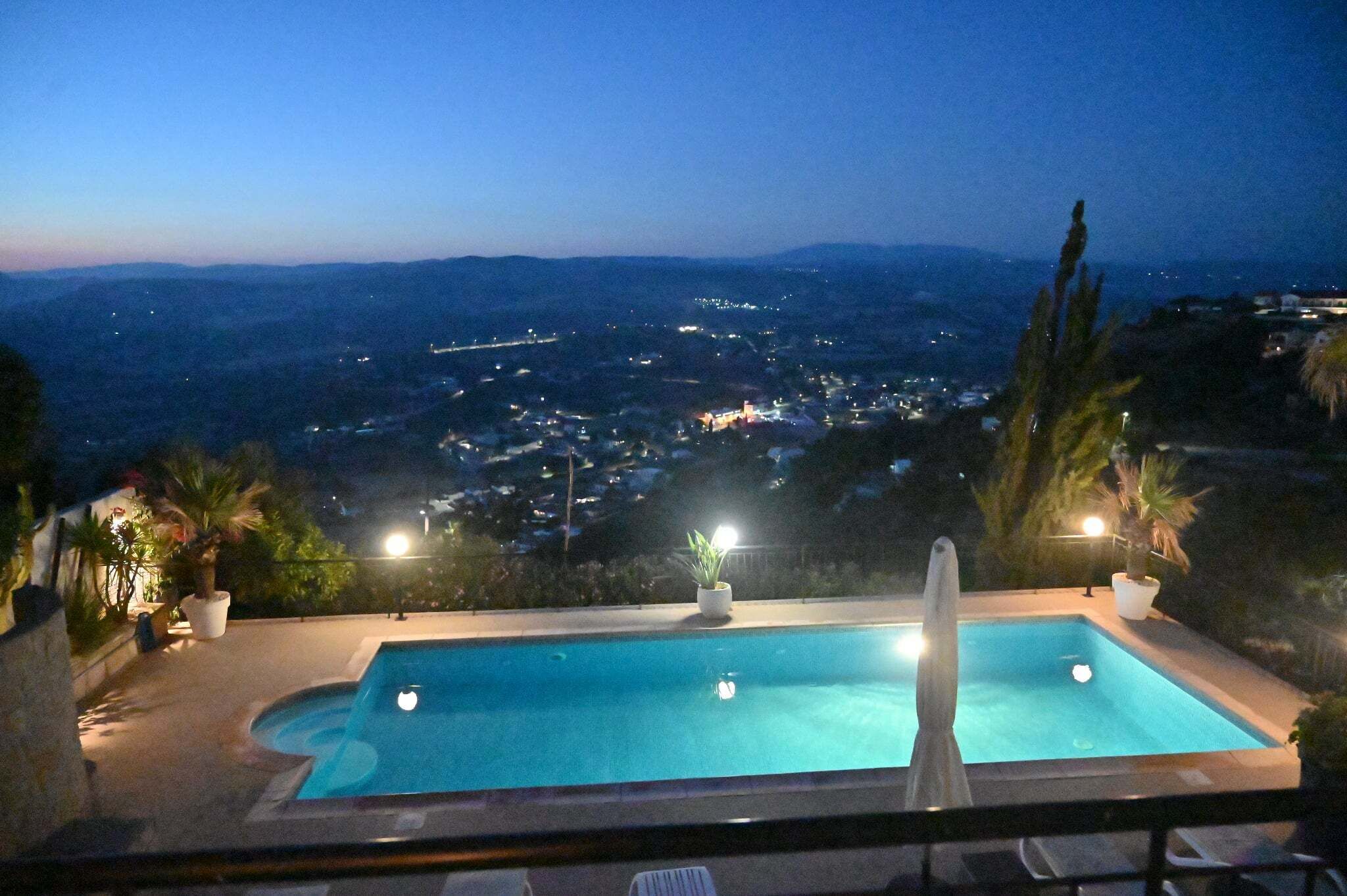 Une piscine offrant une vue sur le paysage urbain illuminé la nuit.