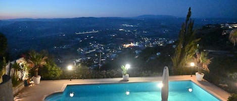A swimming pool with a view of a cityscape at night.