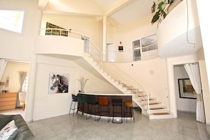 A spacious living area with a staircase, a dining table with chairs, and a painting of a horse. - Stunning 5-bedroom villa with private pool, panoramic sea and mountain views. (Pissouri)