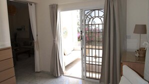 Ein Zimmer mit Stuhl, Lampe, einem Fenster mit Vorhängen und Blick nach draußen.