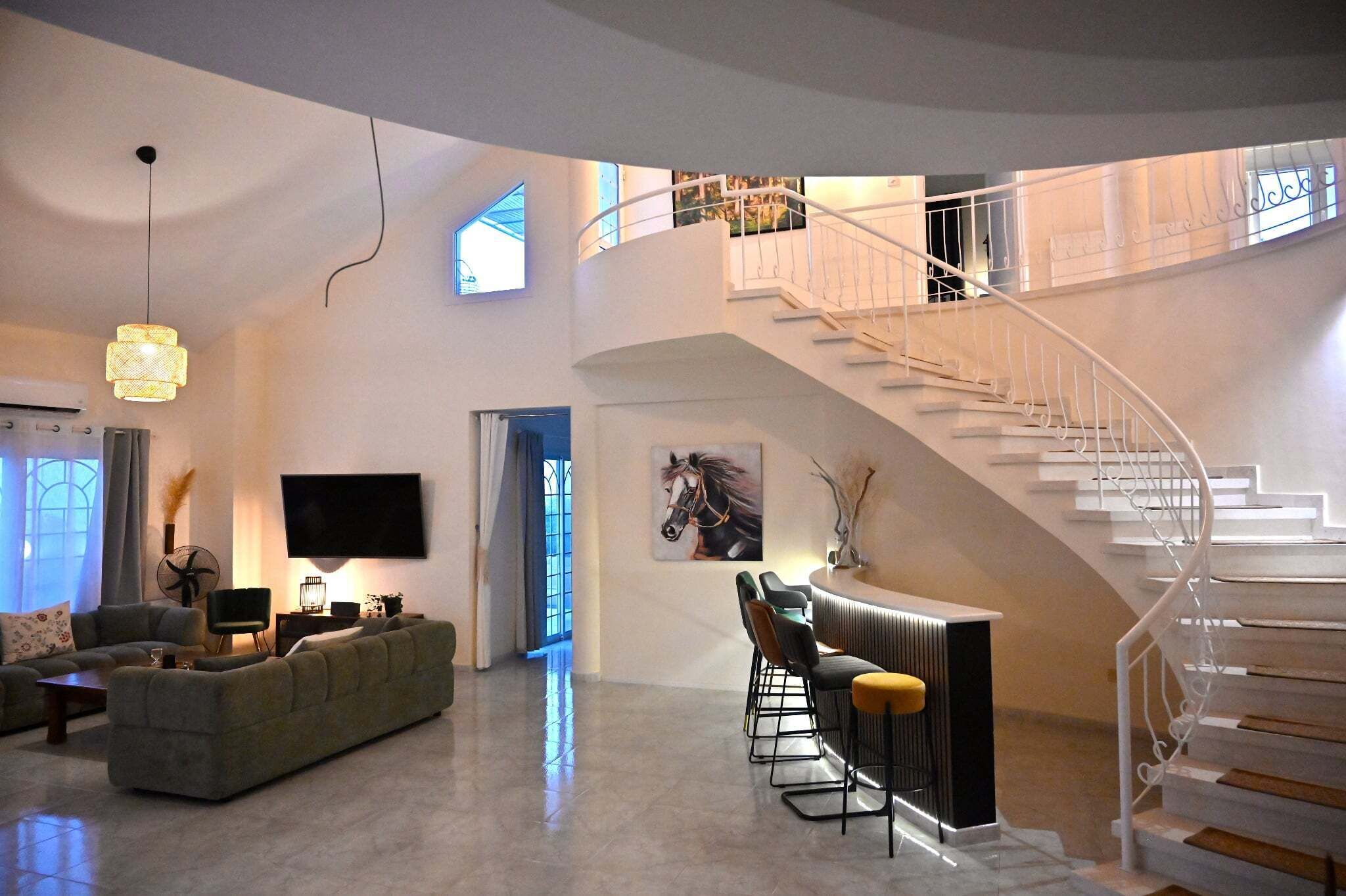 Un vaste espace de vie agrémenté d’un escalier moderne, d’un téléviseur à écran plat et d’un coin salon.