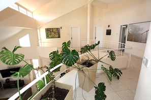 A multi-level interior with a staircase, potted plants, and artwork on the walls. - Stunning 5-bedroom villa with private pool, panoramic sea and mountain views. (Pissouri)