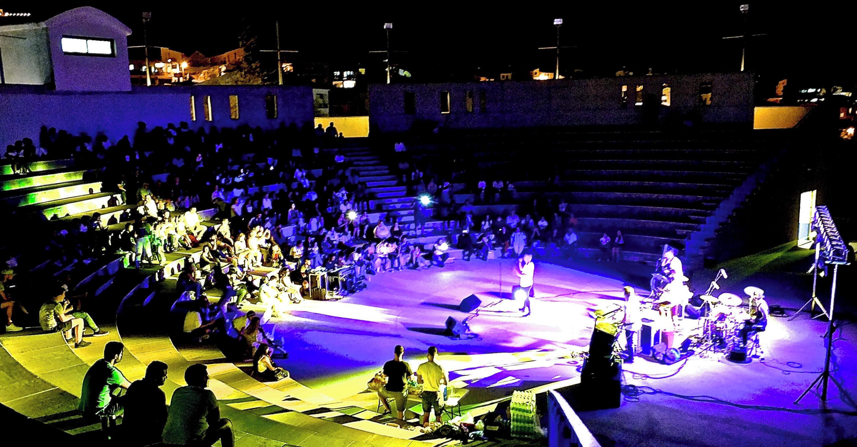 Un anfiteatro al aire libre con asientos escalonados y un escenario.