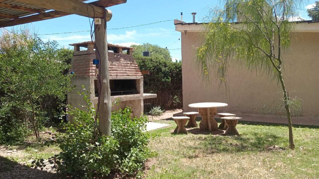 Un espacio al aire libre con una parrilla, mobiliario para exterior y una pérgola.