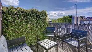 A rooftop terrace with a wooden deck, two benches, a metal fence, and a hedge. - Dartagnan S Vres Eclectic 2BR Home With Terrace (Paris)