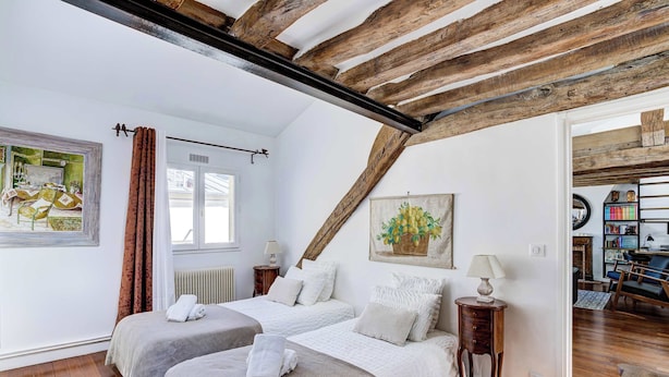 A room with two beds, a window with curtains, a radiator, and a painting on the wall. - Dartagnan S Vres Eclectic 2BR Home With Terrace (Paris)