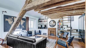 A modern living room with a black leather sofa, wooden chairs, a fireplace, and a bookshelf. - Dartagnan S Vres Eclectic 2BR Home With Terrace (Paris)