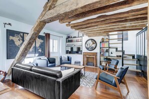 Ein modernes Wohnzimmer mit einer schwarzen Ledersofa, Holzstühlen, einem Kamin und einem Bücherregal.