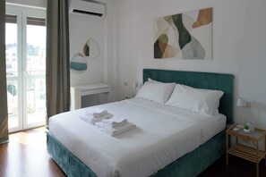 Ein Hotelzimmer mit einem Bett, einem Nachttisch, einer Wand-Klimaanlage und einem Fenster mit Vorhängen.