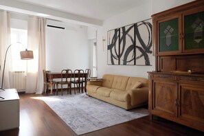 Ein Wohnzimmer mit einer Couch, einem Esstisch, Stühlen, einer Lampe und einem Schrank.