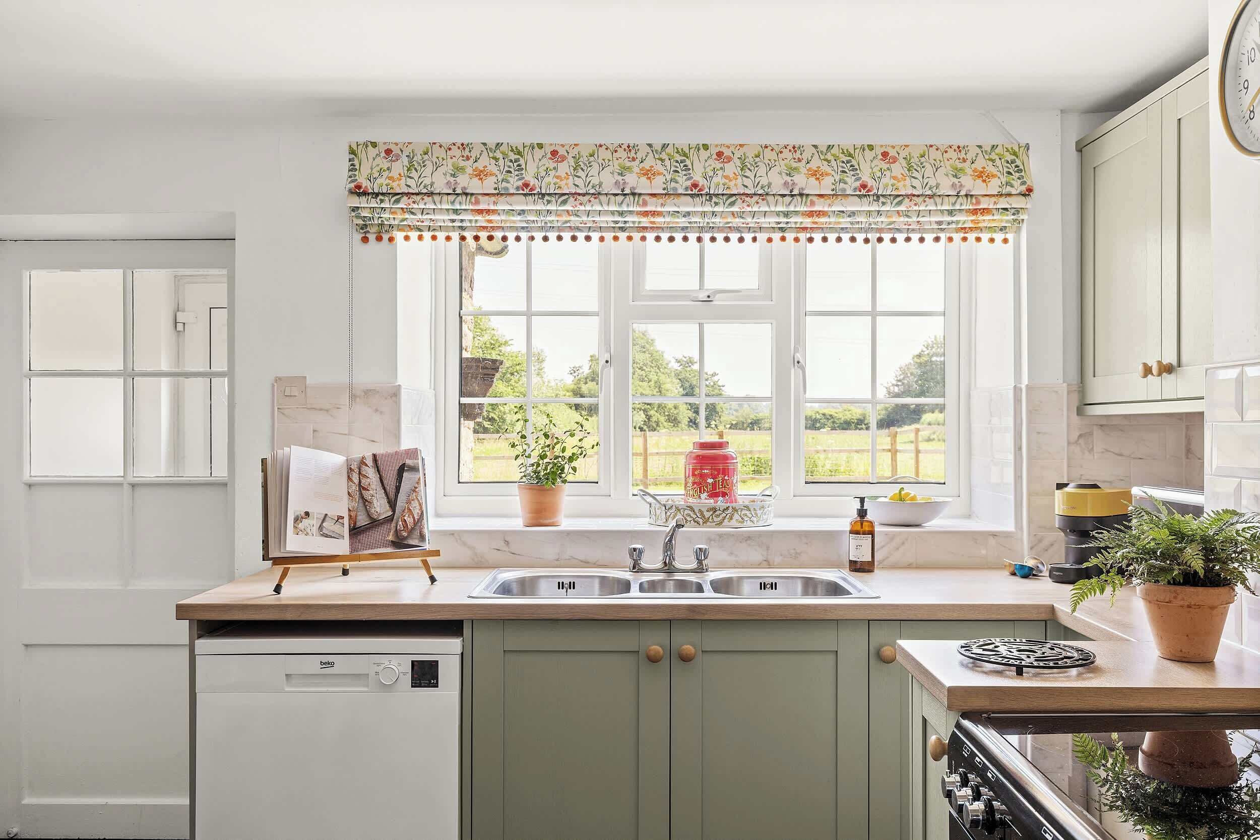Una cocina con ventana, un lavabo, una estufa y un lavavajillas.