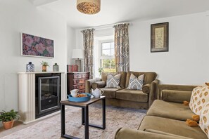 A living room with a fireplace, sofa, and a table with a bowl and teapot. - Cosy Cottage in Rural Location With Lovely Country (Malton)