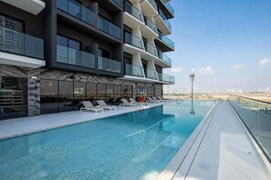 A modern building with a rooftop pool, glass railings, and a clear view of the cityscape. - Free Housekeeping Visits During Your Stay - Stayshort - 1 Bed Apartment in JVC That Sleeps 2 With Balcony (Dubai)