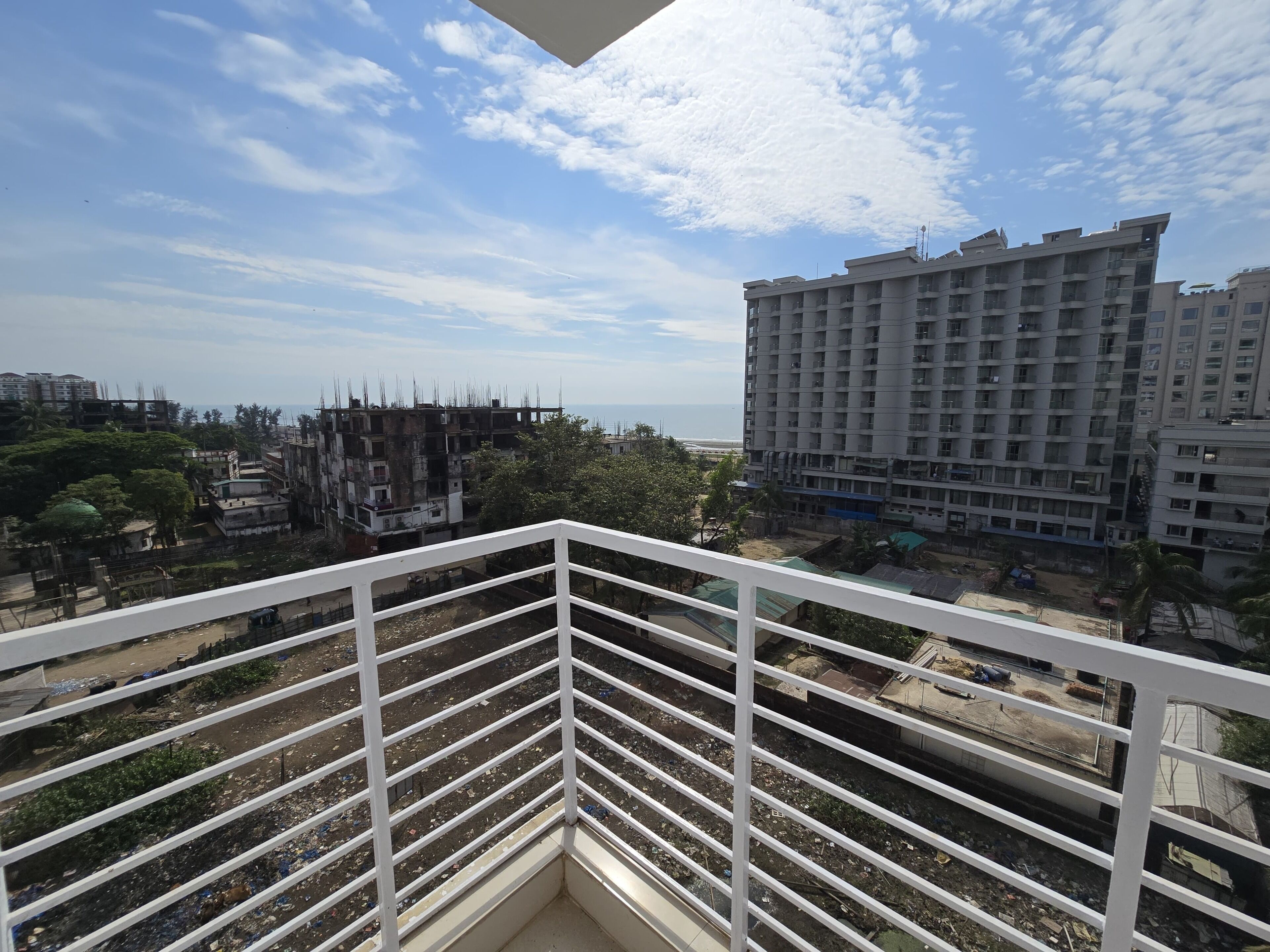 Un balcone con vista sulla città costiera, tra cui grattacieli e una spiaggia.