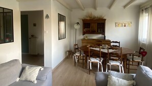 Una sala de estar con un sofá gris, una mesa de centro blanca y un comedor con muebles de madera.