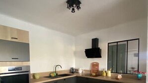 Una cocina moderna con horno empotrado, pileta y campana extractora negra.