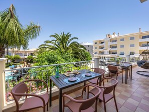 Ein Balkon mit Tisch und Stühlen mit Blick auf einen Pool und üppige Vegetation.