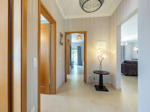 Ein Flur mit Holztüren, einer modernen Leuchte und Blick in einen weiteren Raum mit einer Couch.
