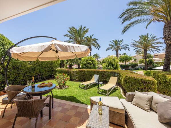 Une terrasse extérieure avec une table ronde, des chaises, un canapé et un parasol.