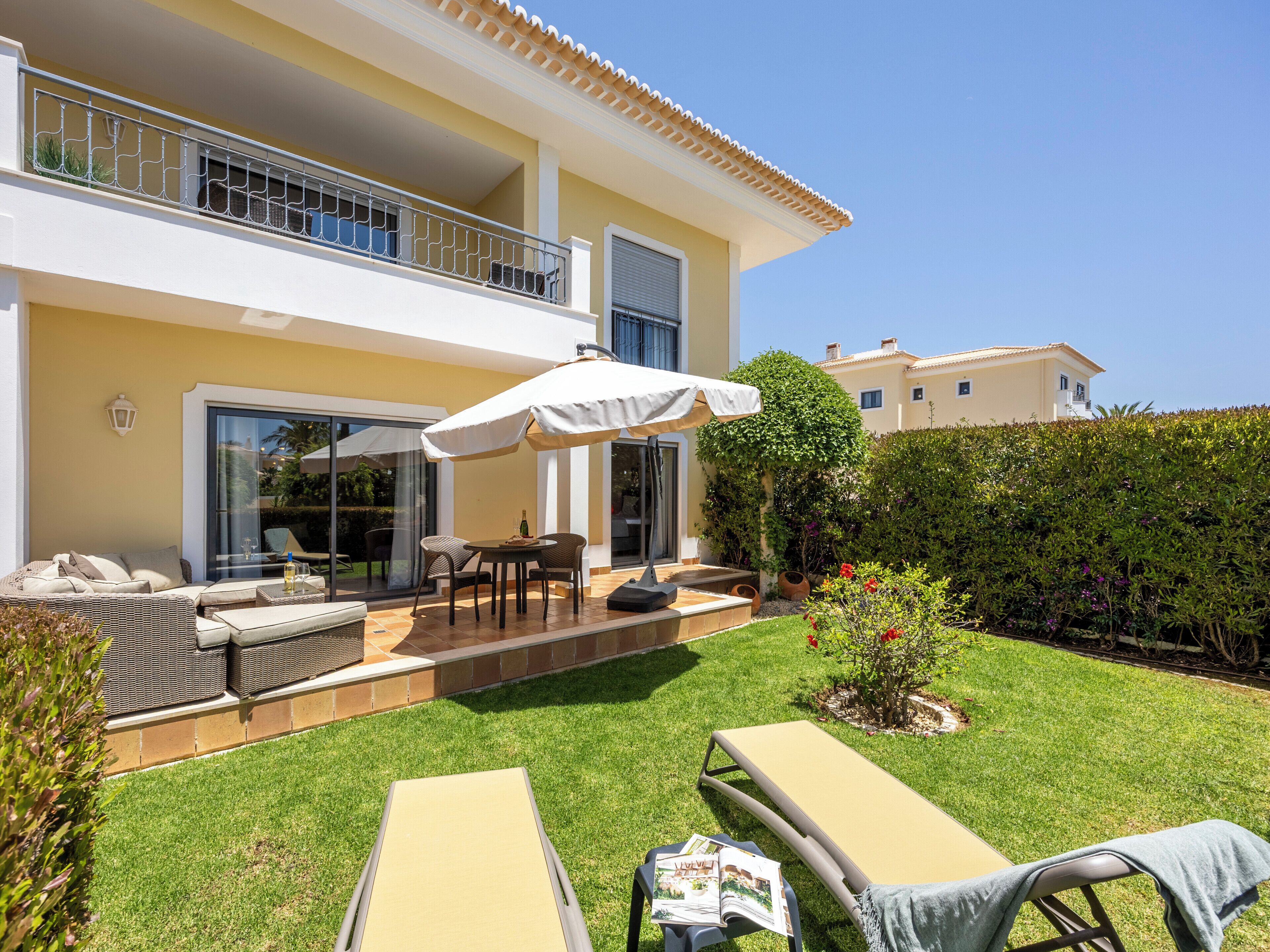 A two-story house with a balcony, outdoor seating, and a well-maintained lawn.