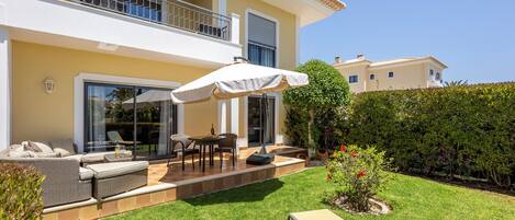 A two-story house with a balcony, outdoor seating, and a well-maintained lawn.