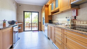 Una cucina moderna con mobili in legno, un piano di lavoro in granito e una porta scorrevole in vetro che dà su uno spazio esterno.
