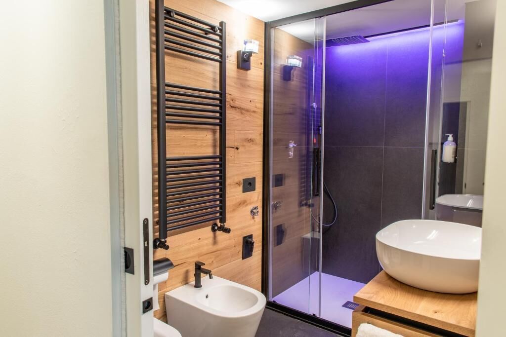 Une salle de bain moderne avec un meuble-lavabo en bois, une cabine de douche en verre et un grand lavabo.
