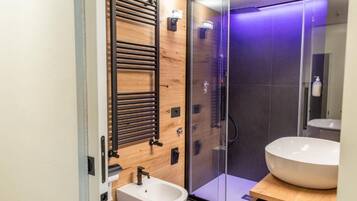 Une salle de bain moderne avec un meuble-lavabo en bois, une cabine de douche en verre et un grand lavabo.