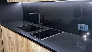 Une cuisine moderne avec des meubles en bois, un plan de travail noir et des appareils électroménagers en acier inoxydable.