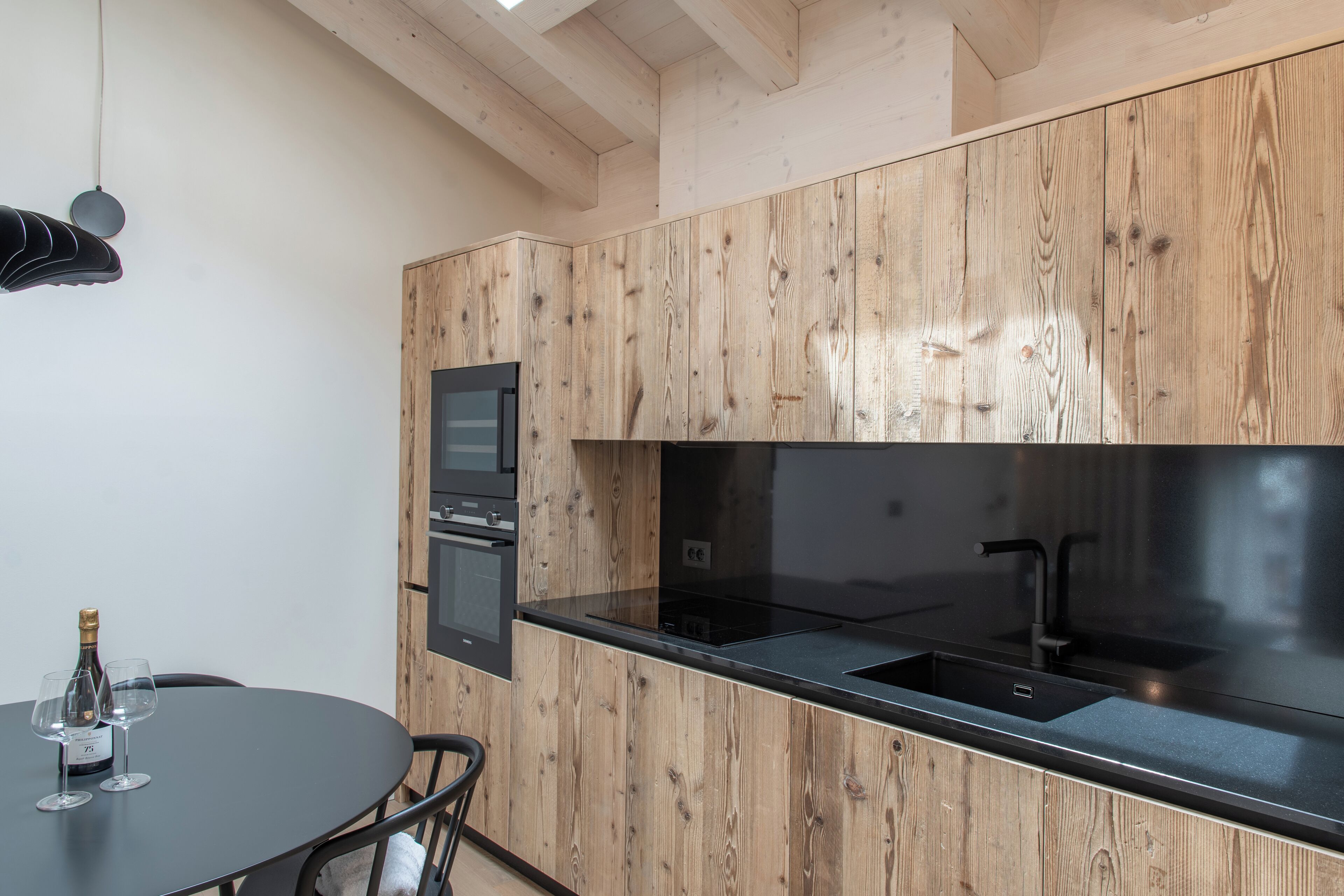 Een moderne keuken met houten kastjes, een zwart aanrecht en roestvrijstalen apparatuur.