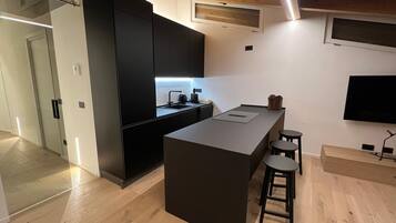 Una cocina moderna con una isla central, taburetes de bar y un televisor de pantalla plana montado en la pared.