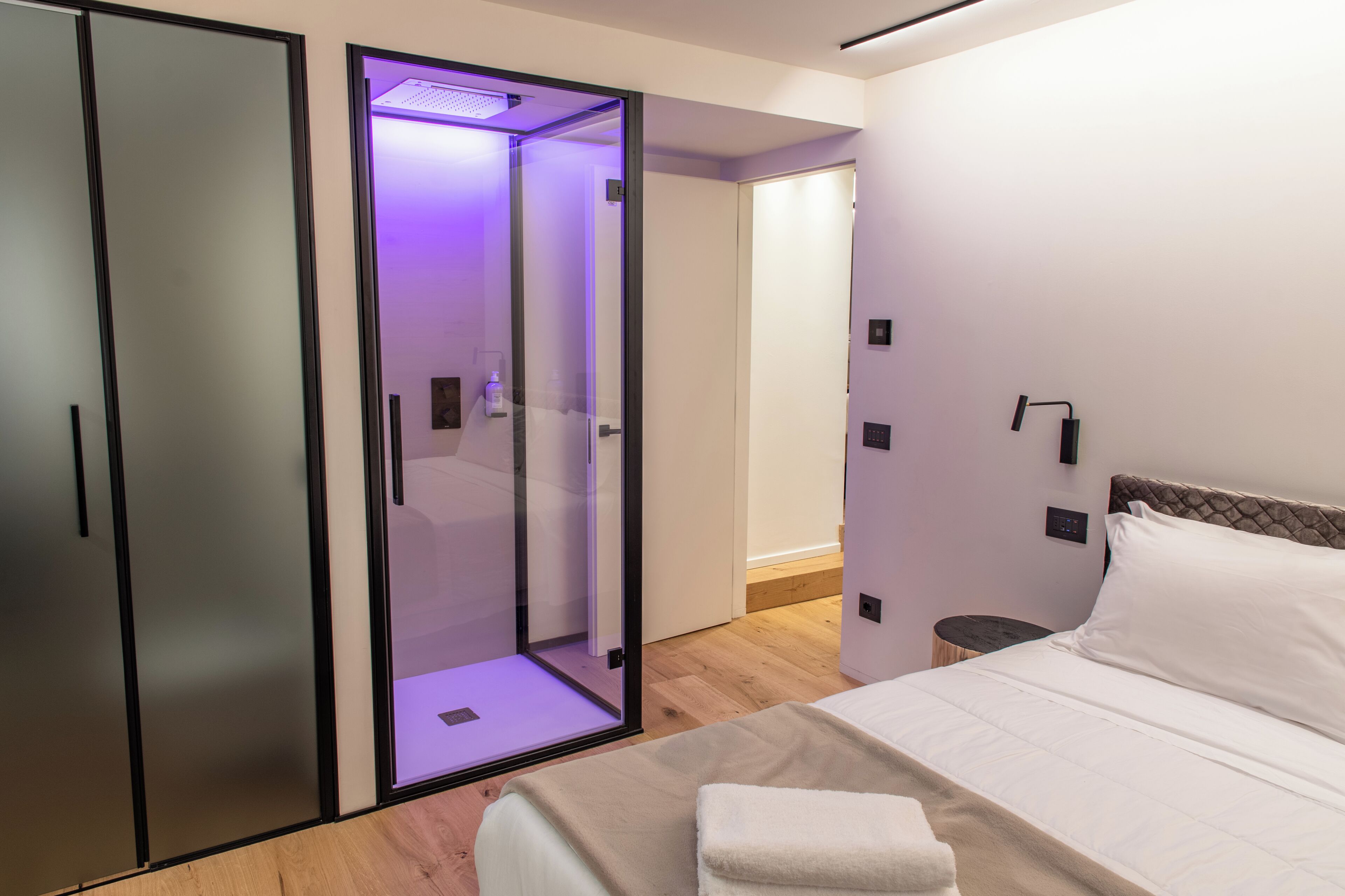 Une chambre moderne avec un lit, une douche en verre et une armoire.